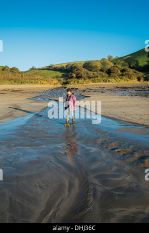 Walker, über einen Bach auf einen Strand nach starken Regenfällen Überschwemmungen. Wonwell, South Devon. UK Stockfoto