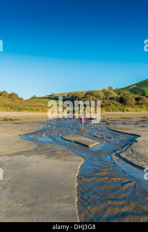 Walker, über einen Bach auf einen Strand nach starken Regenfällen Überschwemmungen. Wonwell, South Devon. UK Stockfoto