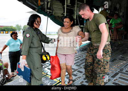 US-Marines unterstützen eine verletzte Filipina Frau von der Rückseite des KC-130J Super Hercules Transportflugzeug auf Villamor Air Base 11. November 2013 in Manila, Philippinen. Die USA trat Hilfsmaßnahmen nach den Verwüstungen durch Super Taifun Haiyan, die geglaubt wird, um über die philippinischen Inseln 10.000 Menschen getötet wurden. Stockfoto