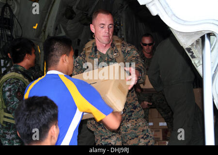 US-Marines übergeben Kisten mit Lebensmitteln von der Rückseite des KC-130J Super Hercules Transportflugzeug auf Villamor Air Base 11. November 2013 in Manila, Philippinen. Die USA trat Hilfsmaßnahmen nach den Verwüstungen durch Super Taifun Haiyan, die geglaubt wird, um über die philippinischen Inseln 10.000 Menschen getötet wurden. Stockfoto