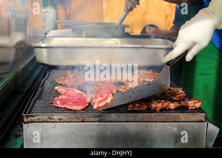 Ein Koch kippt ein sizzling hot Grill Steaks. Stockfoto