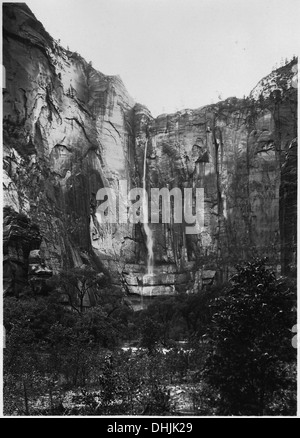 Ein Wasserfall stürzt aus einem hängenden Tal im Tempel von Sinawava, der während eines Regensturms erfasst wurde, und veranschaulicht die natürliche Schönheit und den dynamischen Wasserfluss im Zion-Nationalpark. Stockfoto