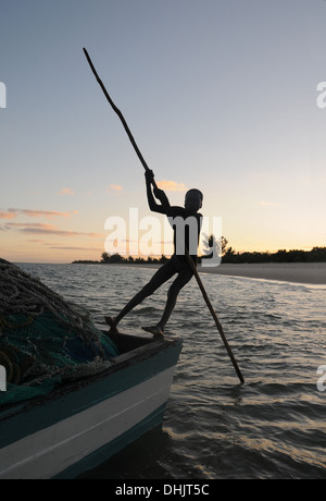 Fischer bei Sonnenaufgang steuert seine Dhau ins offene Wasser. Benguerra Island, Bazaruto Archipel. Mosambik. Ost-Afrika. Stockfoto