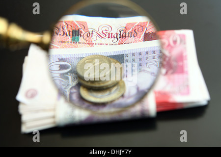 Ein Vergrößerungsglas Glas Lupe Sterling Münzen und Banknoten Stockfoto