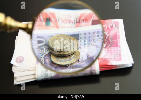 Ein Vergrößerungsglas Glas Lupe Sterling Münzen und Banknoten Stockfoto