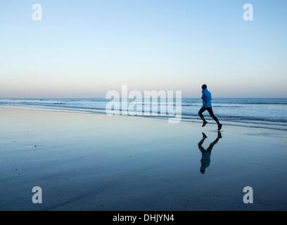 Mann, jogging am Strand bei Sonnenaufgang Stockfoto