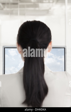 Geschäftsfrau, sitzen vor einem Computer mit Wolken und Himmel auf dem monitor Stockfoto