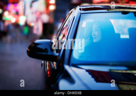 Ruhige Frau, die durch Autofenster im Nachtleben Stadt Stockfoto