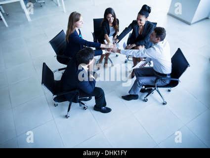 Business-Leute sitzen in einem Kreis mit Händen zusammen jubeln Stockfoto