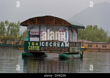 Eine schwimmende geschlossen Garküche im Dal-See in Srinagar, Kaschmir, Indien mit Hausboote, Bäume und Berge im Hintergrund. Stockfoto