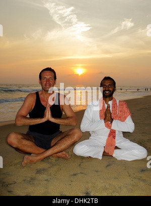 Indische Yoga-Lehrer und Schüler am Strand in Varkala, Indien. Stockfoto