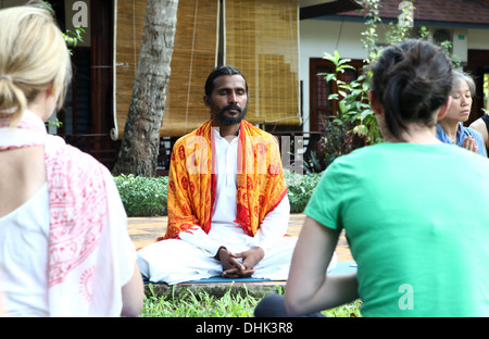 Yoga-Lehrerin sitzt in einem Resort-Garten mit seinen Schülern in Varkala, Indien zu meditieren. Stockfoto