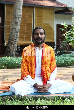 Yogalehrer sitzen und singen von Mantras in einem Resort-Garten in Varkala, Indien. Stockfoto