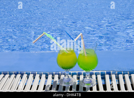 Gläser mit Cocktail am Rand des Pools stehen Stockfoto