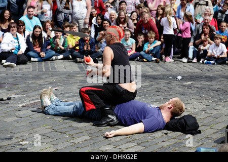 Der Straßenkünstler Mighty Gareth jongliert mit einem Messer und Kugeln über einem Freiwilligen während des Edinburgh International Festival Fringe, Schottland, Großbritannien Stockfoto