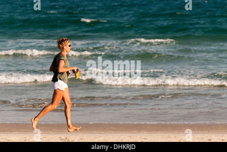 Reife Frau am Strand joggen. Stockfoto