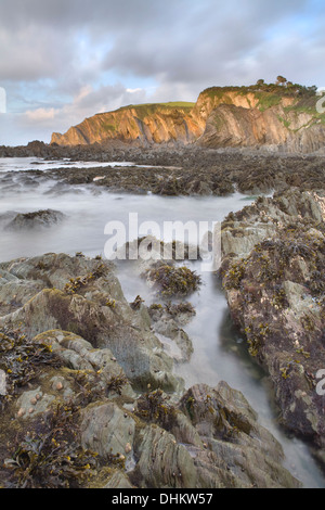 Sonnenuntergang auf den Felsen am Lee Bay, North Devon, England bei Ebbe zeigt die schroffen Felsen unter dem Meer. Stockfoto