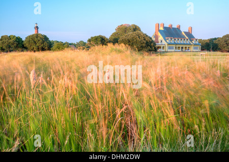 Currituck Beach Lighthouse und dem Whalehead-Club mit der untergehenden Sonne, die Hervorhebung der wehenden Gräsern im Vordergrund. Stockfoto