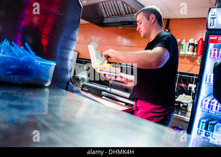 Ein Mann arbeitet in einem Fish &amp; Chips-Shop, UK Stockfoto