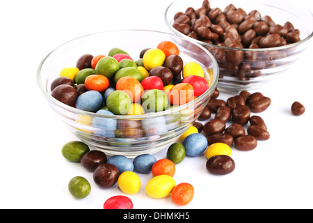 Bunte Bonbons mit Rosinen und Erdnüsse in Vasen isoliert auf weißem Hintergrund. Stockfoto