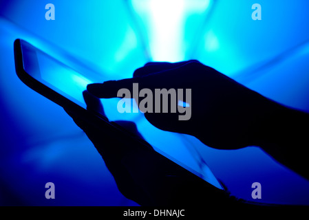 Silhouette von Hand mit Tablet-pc auf blau Stockfoto