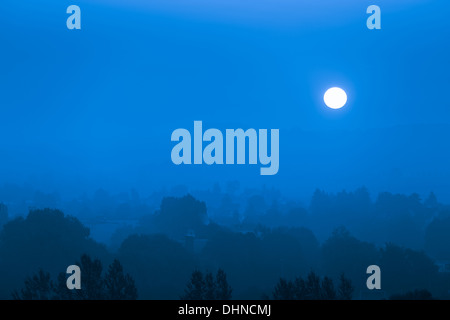 Mondaufgang über der blauen Nebel Stadt Stockfoto