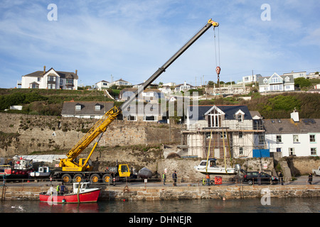 Ein großer gelber Kran heben Boote aus Portreath Hafen während der Winter sich nähert, Cornwall England. Stockfoto