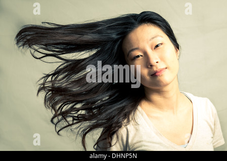 Junge Frau ihr Haar streichen und posiert mit Mode Ton und Hintergrund Stockfoto