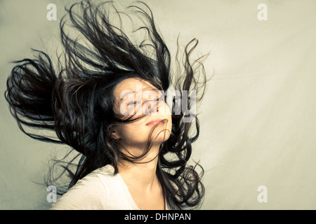 Junge Frau ihr Haar streichen und posiert mit Mode Ton und Hintergrund Stockfoto