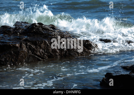Wellen brechen sich am Felsen Stockfoto