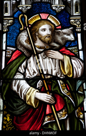 Das Christentum. Ein Buntglasfenster mit Jesus als Hirte hält einen Gauner in der Kirche St Mary die Jungfrau, Piddlehinton, Dorset, England. Stockfoto