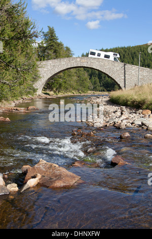 Fluss Gairn, Schottland. Der Fluss Gairn in der Nähe von Gairnshiel Lodge mit einem Wohnmobil auf der Straßenbrücke im Hintergrund. Stockfoto