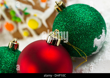 Closeup horizontale Foto von oben der Rote Christbaumkugel mit Lebkuchenhäuser, umgeben von Pulverschnee im Hintergrund Stockfoto