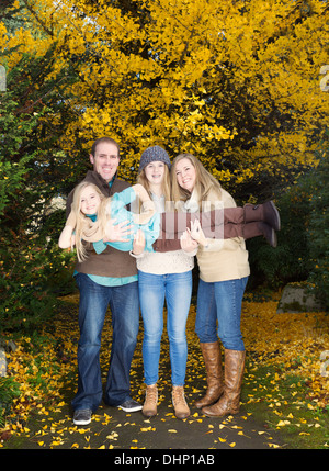 Vertikale Foto von ihre kleinsten Tochter bei einem Spaziergang im Park bei einem Herbsttag Familienholding Stockfoto