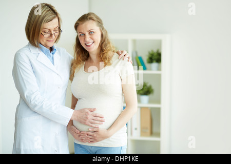 Glücklich schwangere Frau und ihr Arzt nach regelmäßigen Untersuchung im Krankenhaus Stockfoto