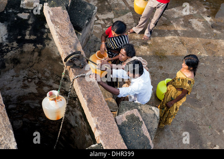 Indische Frauen und Männer ziehen Wasser aus einem Brunnen in einem indischen Dorf Straße. Andhra Pradesh, Indien Stockfoto