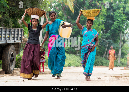Glücklich lächelnd, indische Frauen und Mädchen trägt einen Wasserkrug und Körbe in einem indischen Dorfstraße. Andhra Pradesh, Indien Stockfoto
