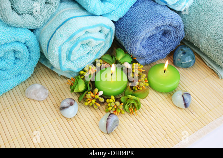 Stapel von Handtüchern, Kerzen, Steinen auf Matten Hintergrund. Stockfoto