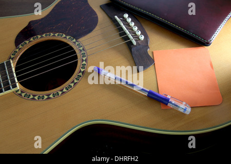 Das Bild Notebook orange Papier und Stift auf der Gitarre. Stockfoto