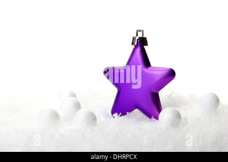 lila Weihnachtskugel als Weihnachtsstern auf Schnee Stockfoto