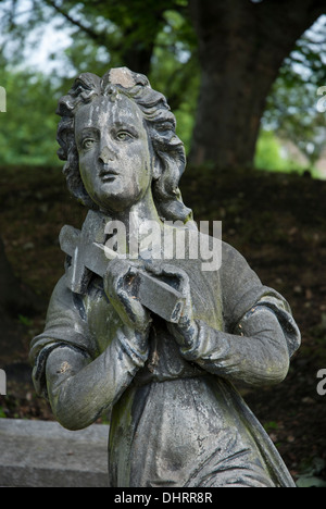 Verwitterte und beschädigte Statue, die eine Frau mit einem Kreuz, Teil eines Denkmals in North Merchiston Burial Ground, Edinburgh. Stockfoto