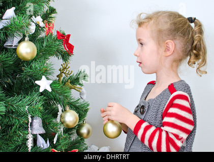 Kleines Mädchen schmückt den Weihnachtsbaum Stockfoto