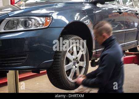 Kfz-Mechaniker ändern Sommerreifen und Winterreifen auf Rädern des Fahrzeugs auf Rampe in der Montagehalle von Reifenzentrum Montage Stockfoto