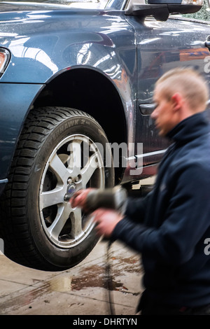 Kfz-Mechaniker ändern Sommerreifen und Winterreifen auf Rädern des Fahrzeugs auf Rampe in der Montagehalle von Reifenzentrum Montage Stockfoto