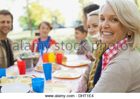 Porträt von glücklich Reife Frau mit Familie am Esstisch im park