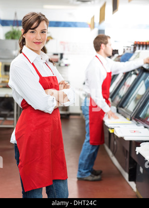 Weibliche Metzger stehend Arme verschränkt im Store Stockfoto