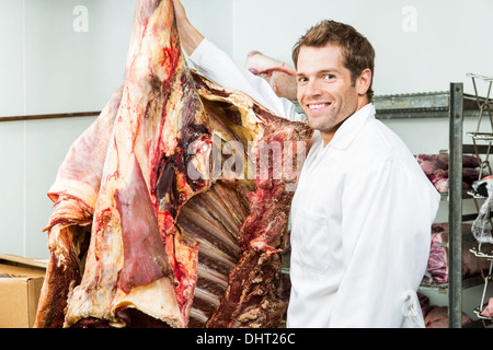 Metzger neben Rindfleisch in Kühler Stockfoto