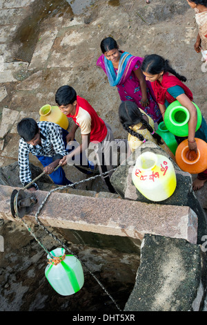 Indische Mädchen und jungen zeichnen Wasser aus einem Brunnen in einem indischen Dorf Straße. Andhra Pradesh, Indien Stockfoto