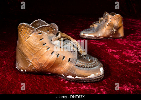 Ein paar alte, antike bronziert Babyschuhe auf klassische rote Pannesamt. Stockfoto