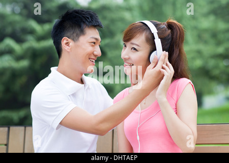 Junges Paar Musikhören im park Stockfoto